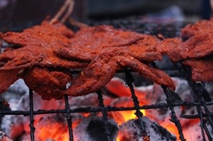 Suya, a beef skewer in suya spice cooking over hot coals